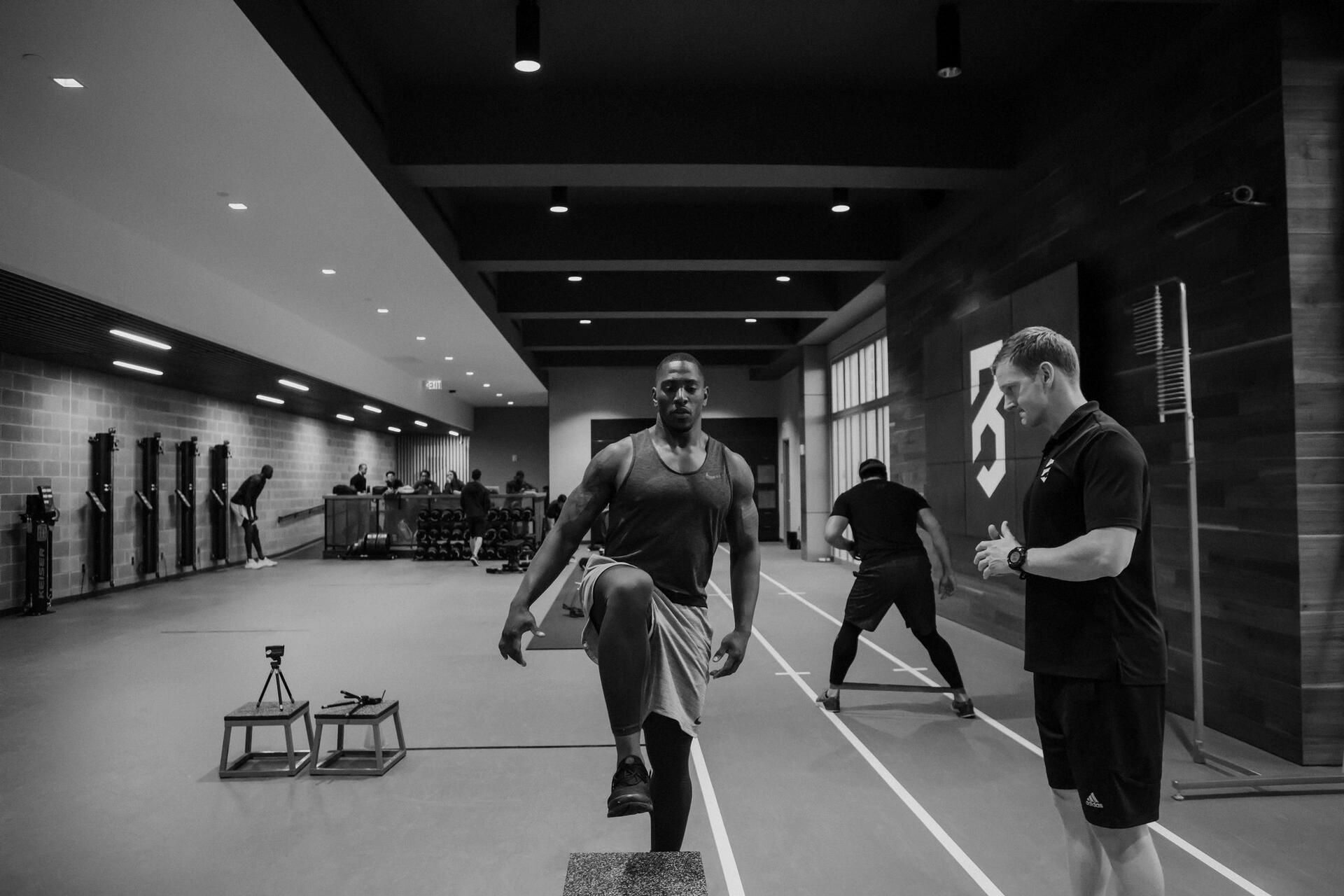 P3 Atlanta facility floor, athlete working with a coach beside the sprint track, black and white