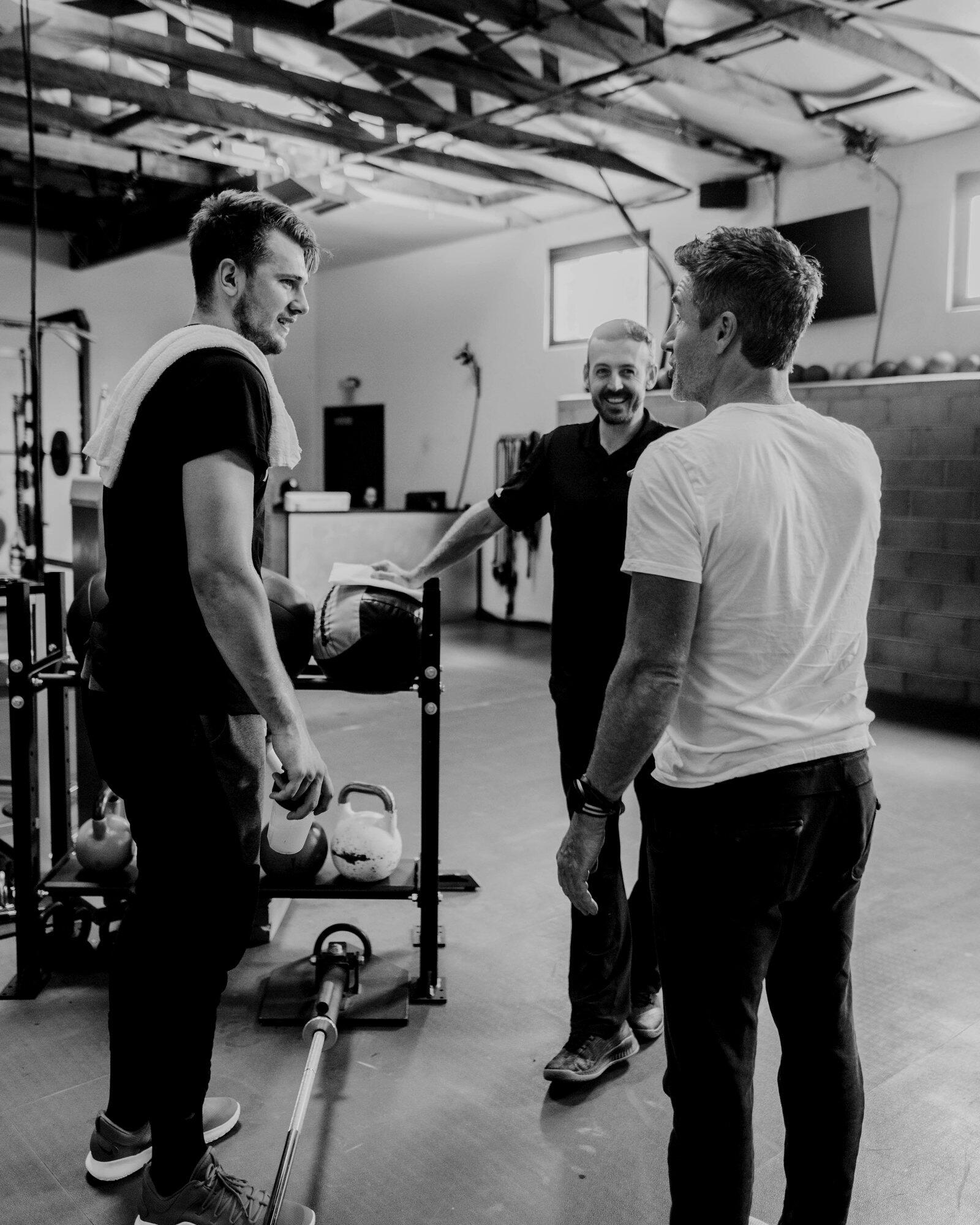 Luka Doncic talking with Dr. Marcus Elliott and a P3 coach in the Santa Barbara gym, black and white